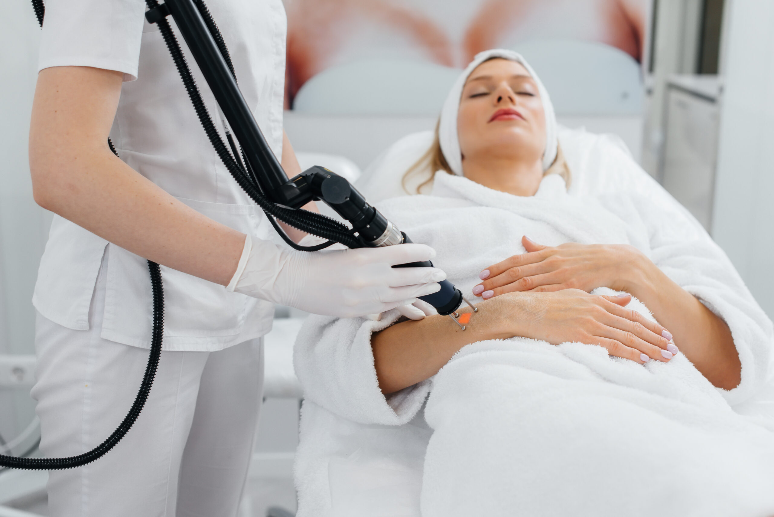 A young girl gets carbon peeling for the skin of her hands in a beauty salon. Laser pulses cleanse the skin. Hardware cosmetology. The process of photothermolysis, warming the skin